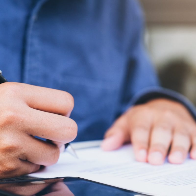 Crop ethnic businessman signing papers.